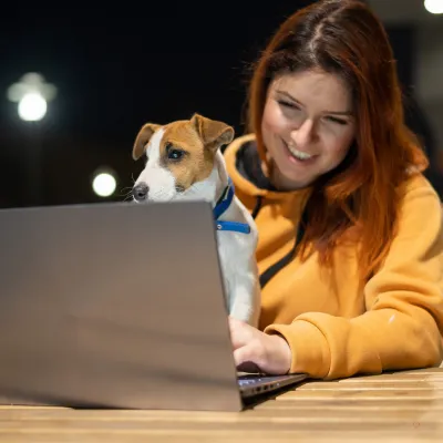 lady siting at a computer with her dog she is smiling